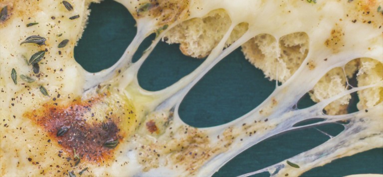A close up of a cheesy garlic bread being pulled apart
