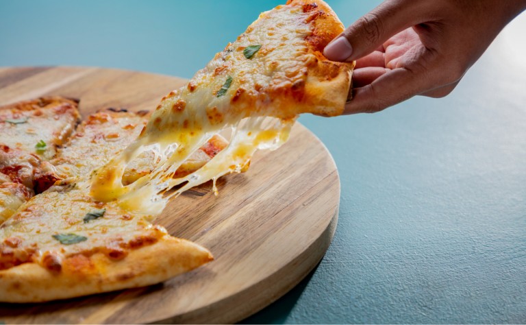 Someone pulling a slice of cheese pizza from a board