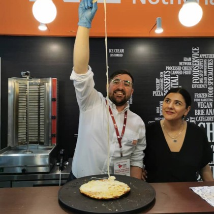 Someone pulling cheese very high from a flatbread